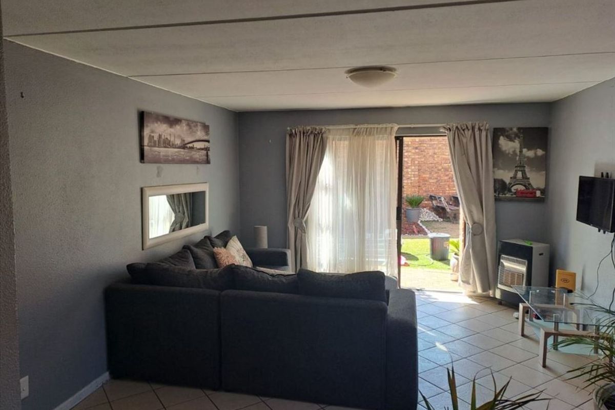 A living room featuring tiled flooring and a sliding glass door providing direct access to the rear garden area.
