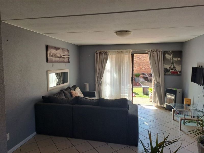A living room featuring tiled flooring and a sliding glass door providing direct access to the rear garden area.