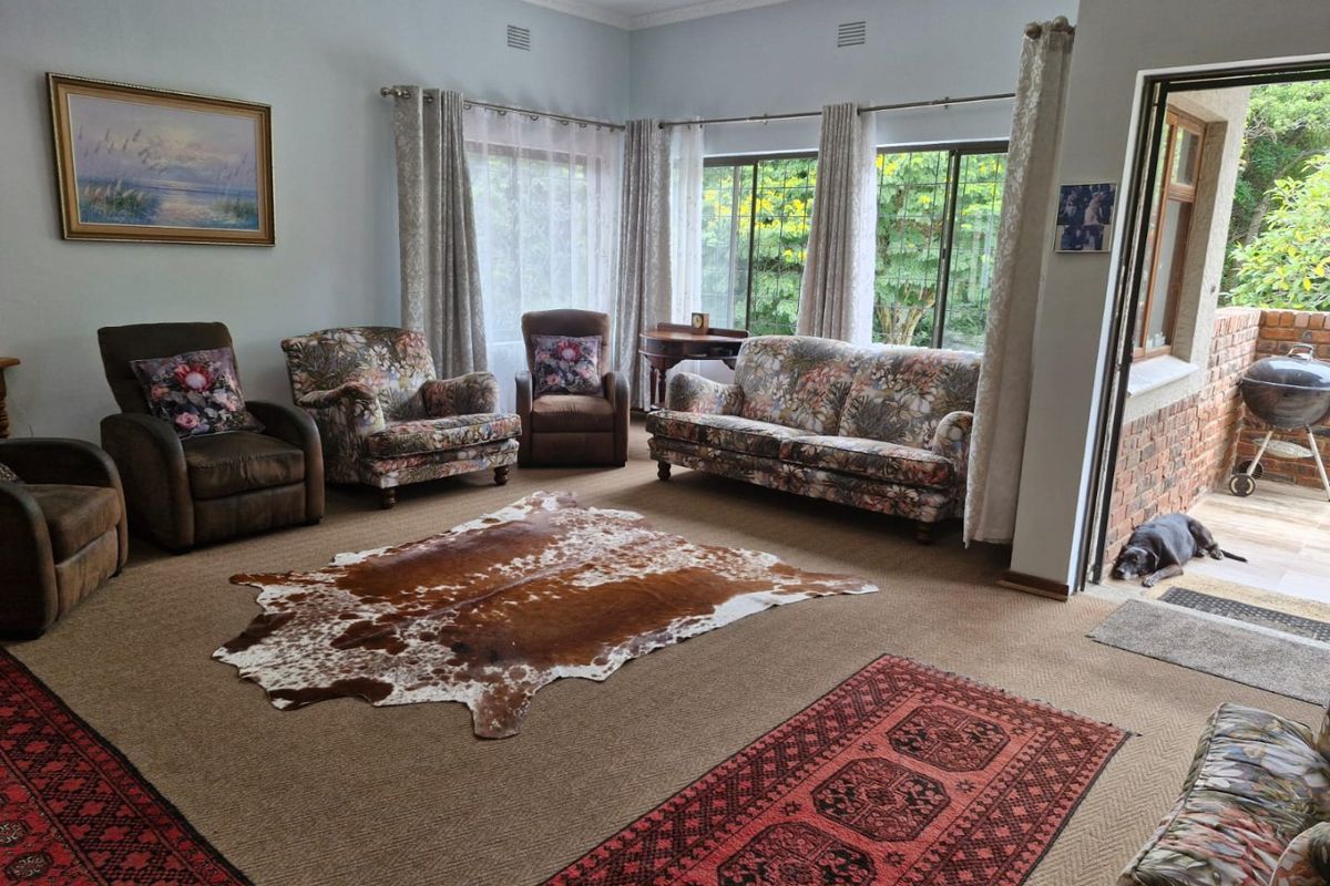 Spacious living room featuring large windows with garden views, crown molding, and direct access to an outdoor patio area.