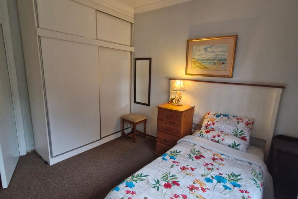 A bedroom featuring built-in sliding door wardrobes, decorative ceiling cornicing, and a ceiling fan.