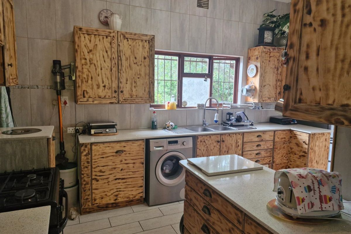 A functional kitchen featuring custom wood-grain cabinetry, stone-look countertops, integrated sink, and tiled flooring with a window providing natural light.