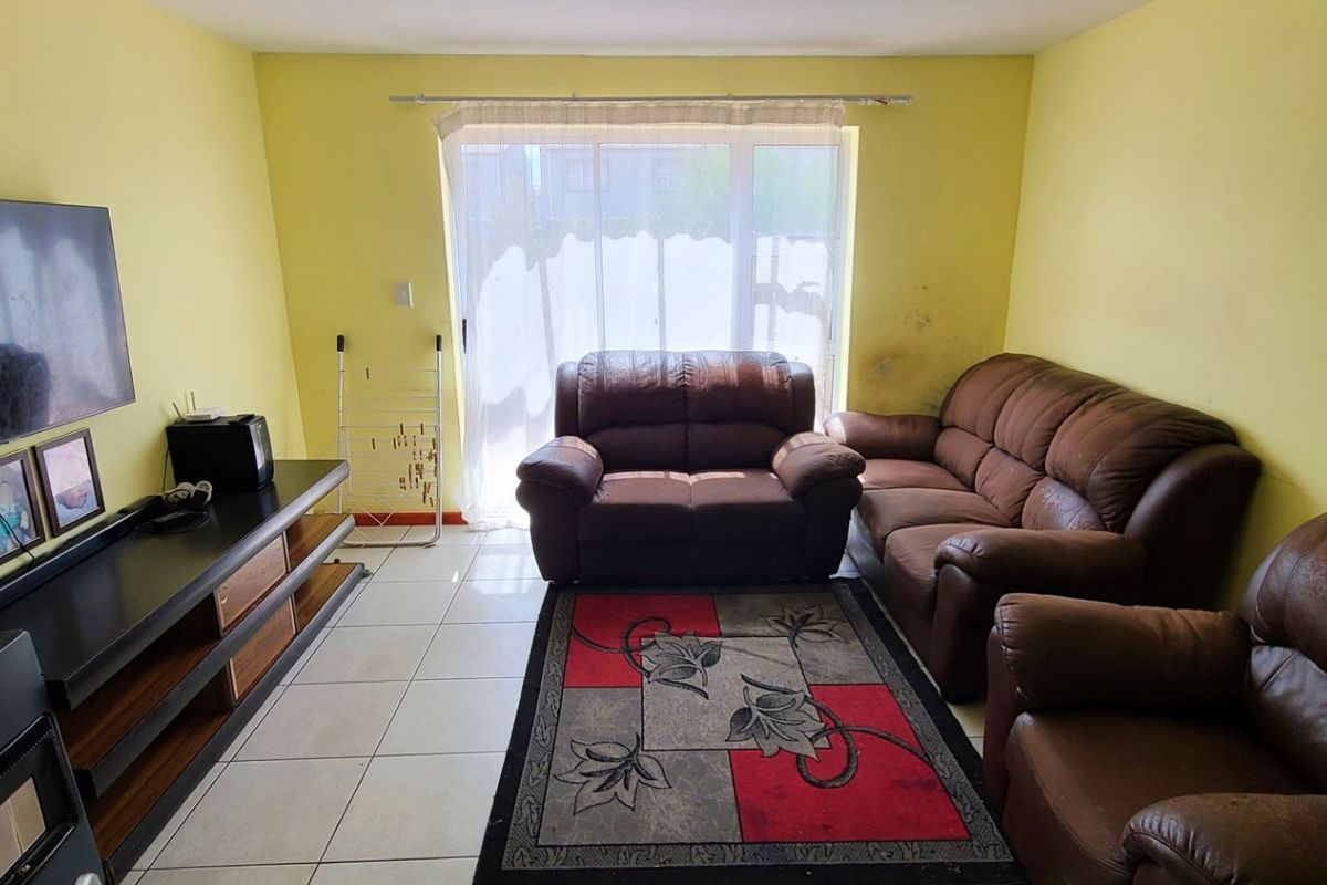 A living room featuring tiled flooring and a large sliding glass door providing natural light.