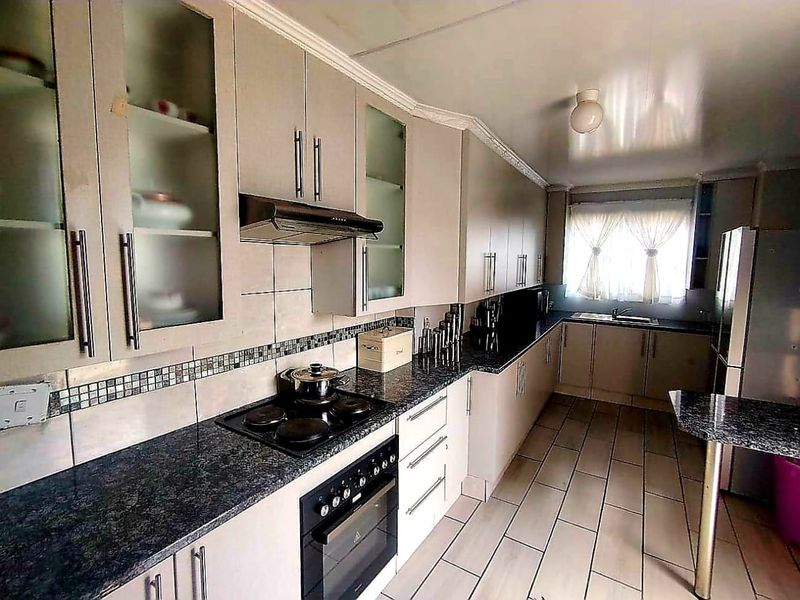 A functional kitchen featuring ample built-in cabinetry, granite countertops, a built-in oven with hob, and tiled flooring throughout.