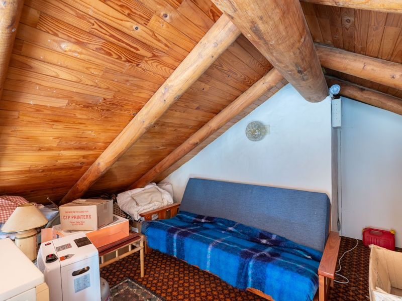 Attic bedroom featuring exposed timber roof beams, wood-paneled ceiling, and carpeted flooring.
