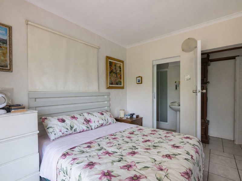 A bedroom featuring tiled flooring and an en-suite bathroom with a pedestal basin.