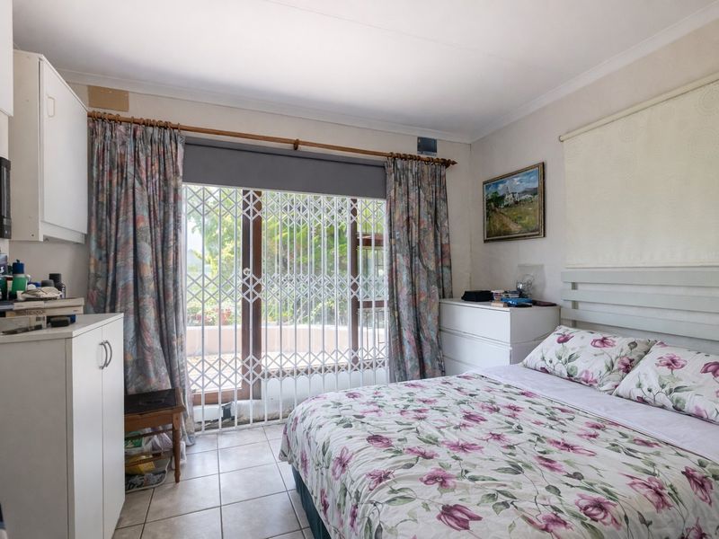A bedroom featuring tiled flooring and a sliding glass door with a security gate, providing access to an outdoor area.