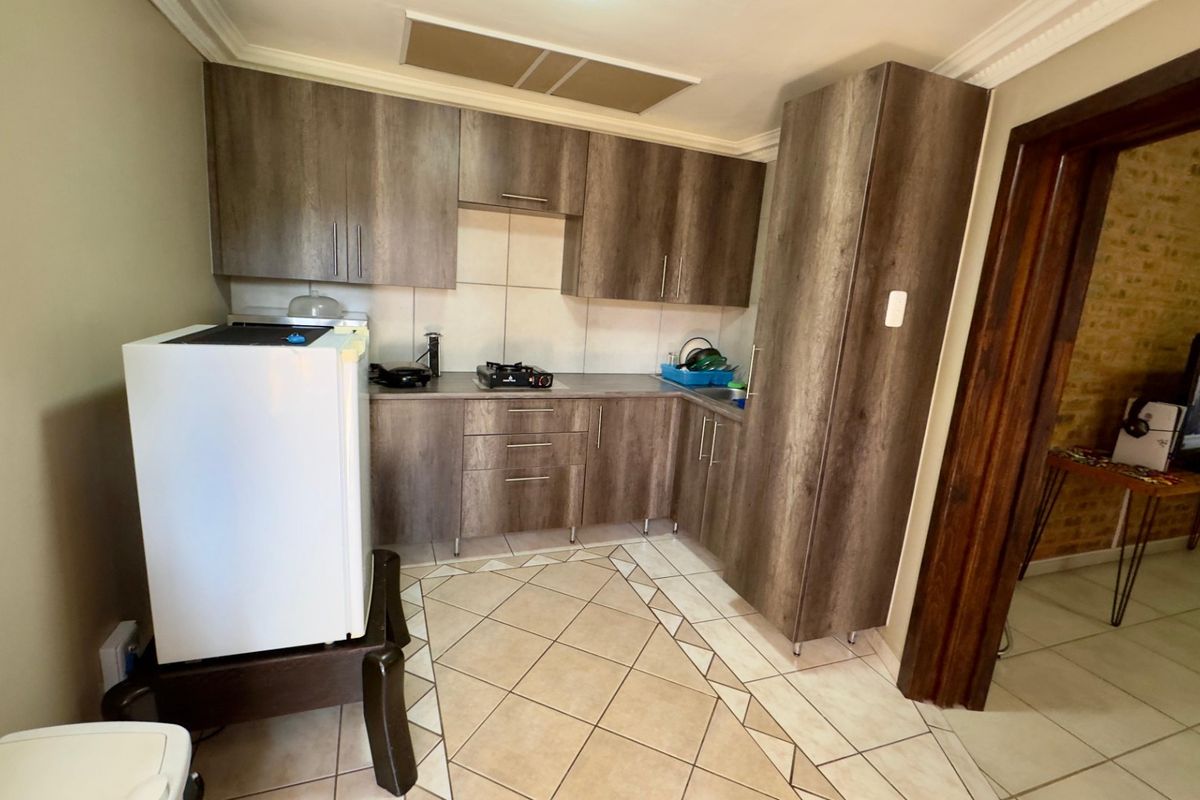 Compact kitchen featuring wood-look cabinetry, tiled backsplash, and tiled flooring, providing a functional preparation area.