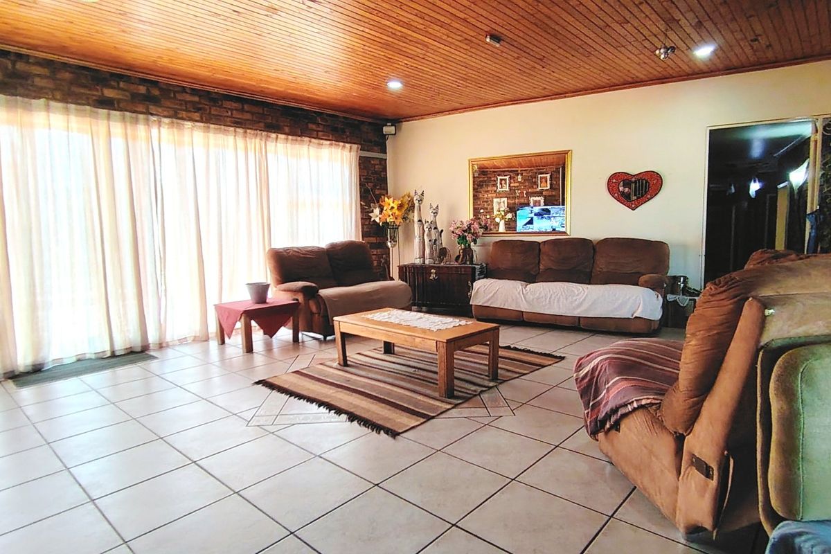 Spacious living room featuring a warm timber ceiling, exposed brick accents, and large sliding glass doors that provide ample natural light.
