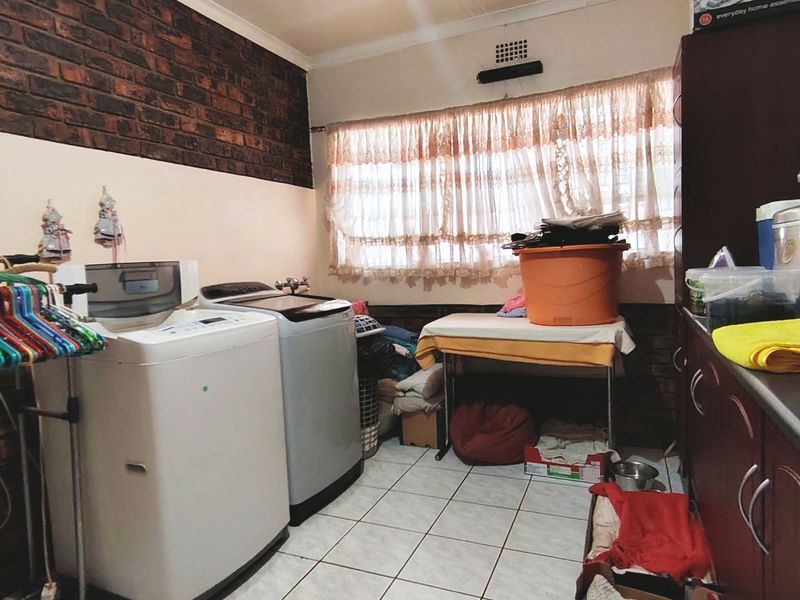 A functional laundry room featuring tiled flooring, exposed brick wall accents, and built-in cabinetry for storage and utility needs.