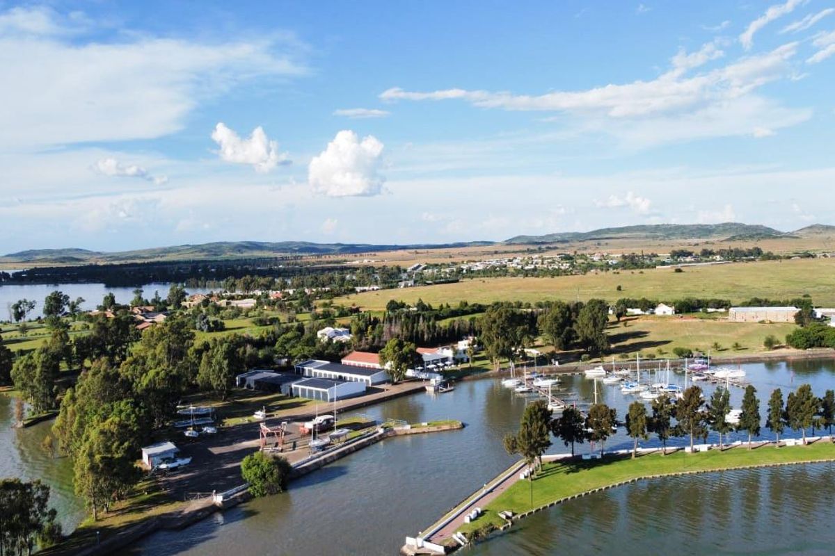 An aerial view of the waterfront property featuring a marina, boat moorings, and direct access to the water, set within a scenic landscape.