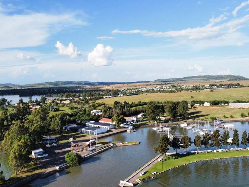 An aerial view of the waterfront property featuring a marina, boat moorings, and direct access to the water, set within a scenic landscape.