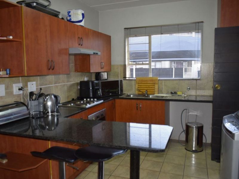 Functional kitchen featuring laminate cabinetry, granite countertops, built-in oven, electric hob, and tiled finishes, offering a practical layout for daily meal preparation.