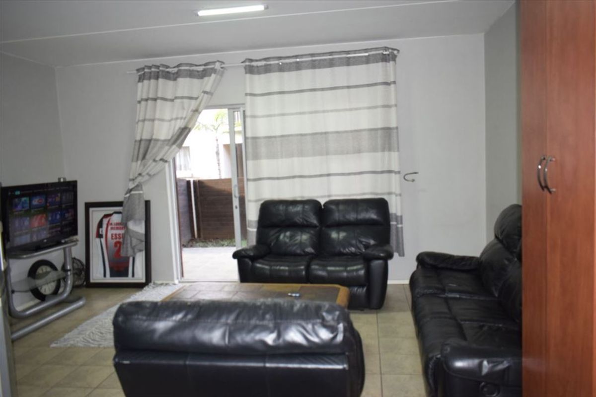 A living room featuring tiled flooring and a sliding glass door providing access to the outdoor area.