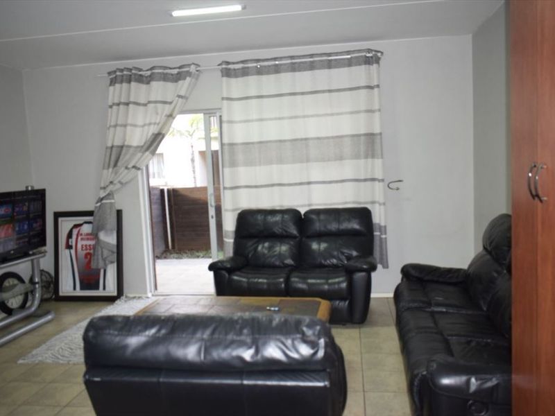 A living room featuring tiled flooring and a sliding glass door providing access to the outdoor area.