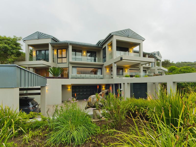 A modern multi-level luxury residence featuring a contemporary facade, glass balustrades, integrated garage, and covered carport with well-maintained landscaping.