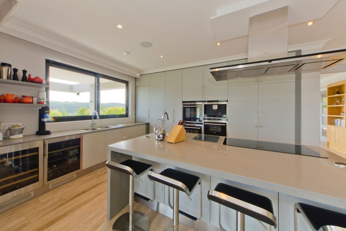 Modern kitchen featuring stone countertops, integrated appliances, induction hob, extractor fan, and a central island with breakfast bar seating.