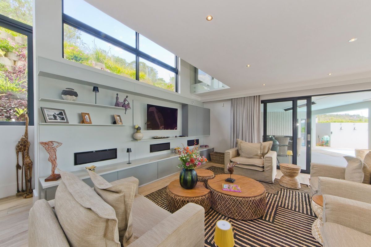 Spacious modern living room featuring custom built-in cabinetry, high ceilings with clerestory windows, and seamless access to the outdoor patio area.