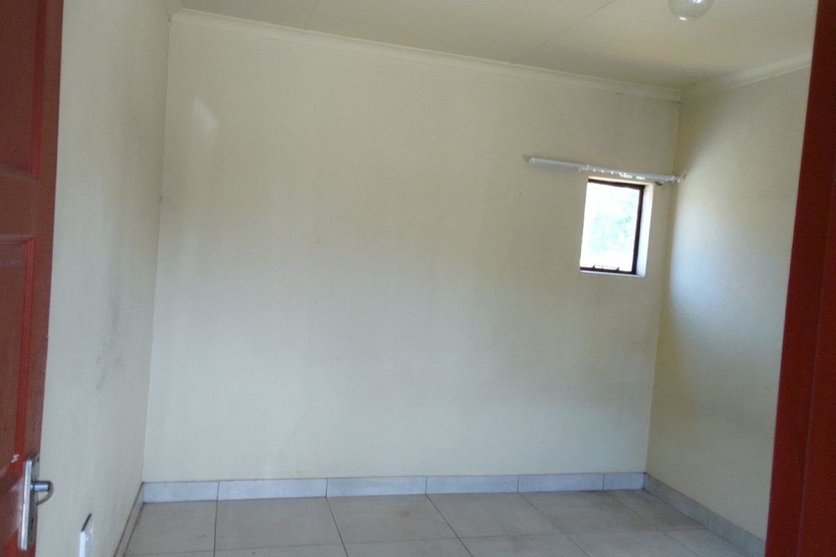 An empty bedroom featuring tiled flooring and neutral walls, providing a blank canvas for potential interior design and furnishing.
