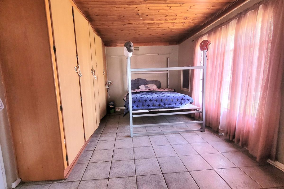 A bedroom featuring tiled flooring, a timber-clad ceiling, and extensive built-in cupboard storage.
