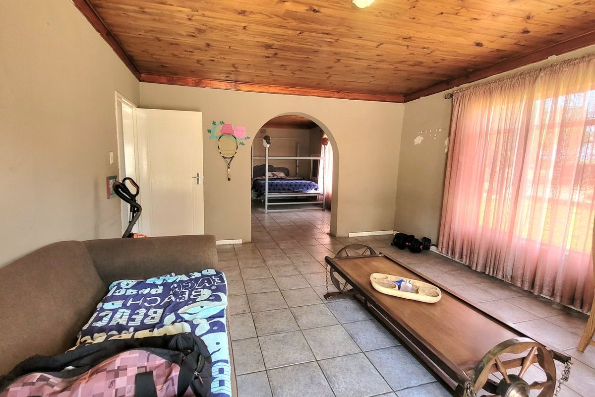 Living room featuring tiled flooring, a timber ceiling, and an arched entryway leading to an adjacent bedroom area.