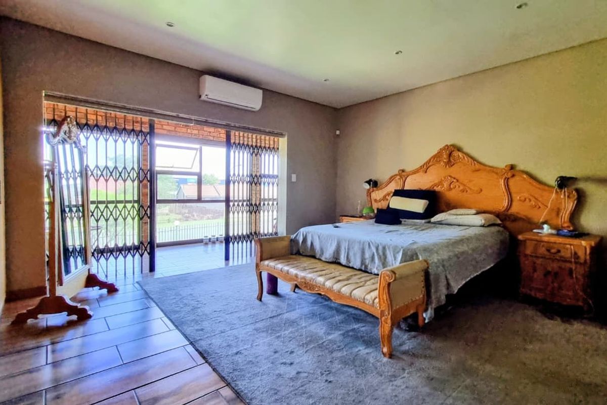 Spacious bedroom featuring built-in cupboards, tiled flooring, and sliding doors leading to an outdoor patio area with security gates.