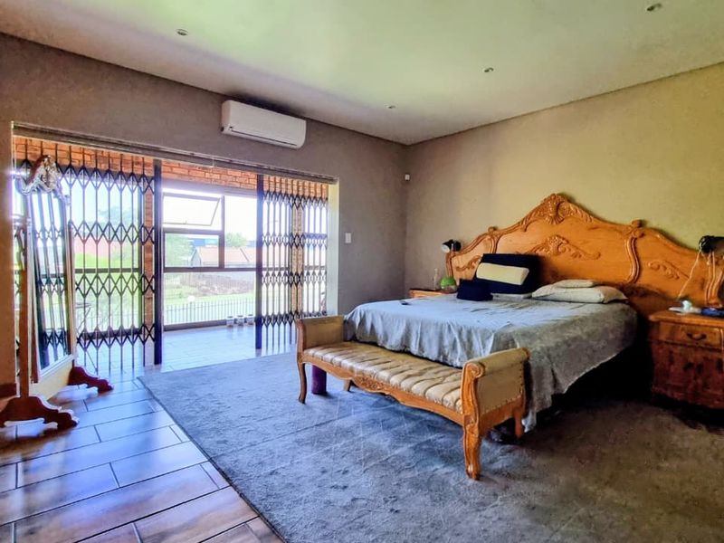 Spacious bedroom featuring built-in cupboards, tiled flooring, and sliding doors leading to an outdoor patio area with security gates.