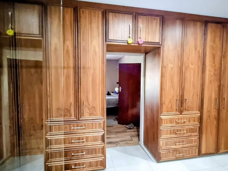 A bedroom featuring extensive floor-to-ceiling built-in wooden cabinetry with integrated drawers and overhead storage compartments.