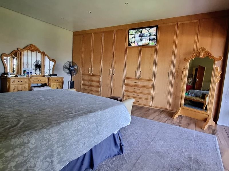 Spacious bedroom featuring extensive built-in wooden cabinetry with integrated storage and direct access to an outdoor area through a security gate.