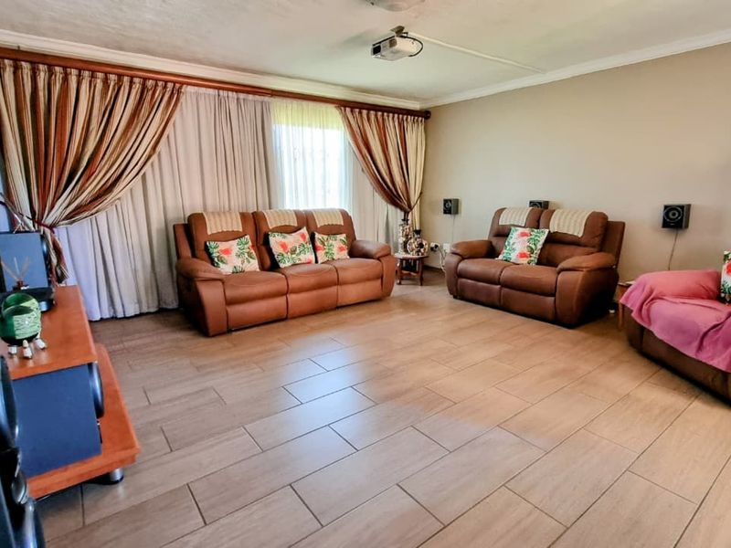 Spacious living room featuring large windows with floor-to-ceiling curtains, tiled flooring, and a ceiling-mounted projector, ideal for a home cinema setup.
