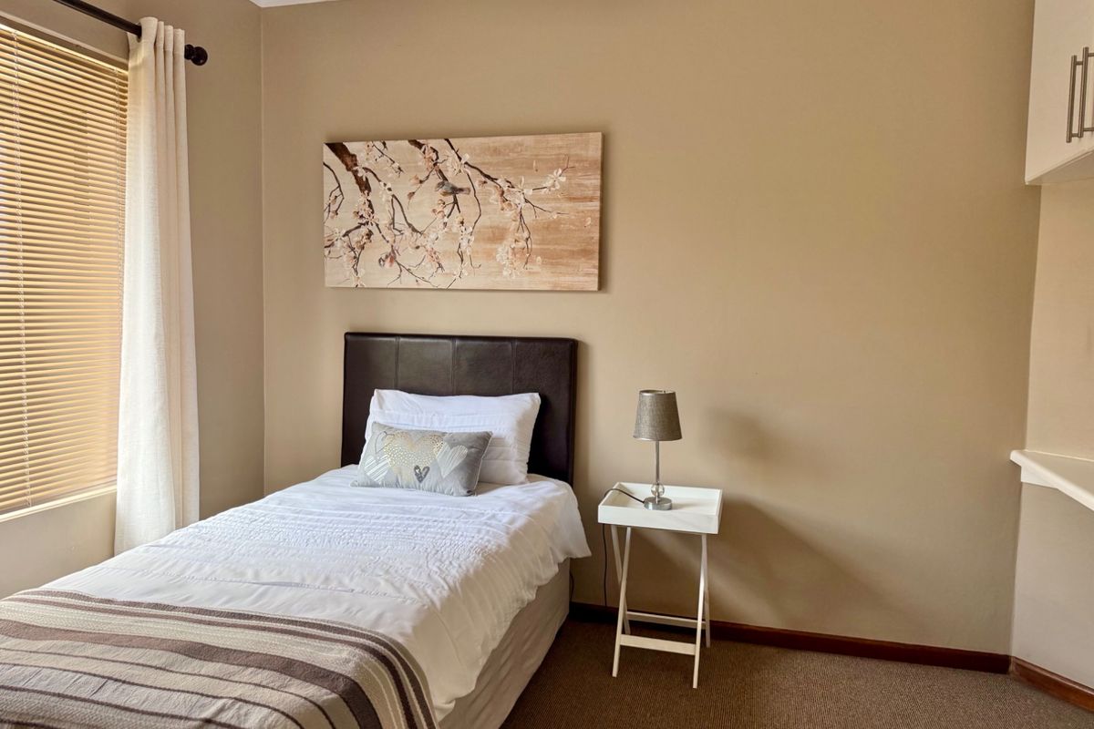 A cozy bedroom featuring neutral wall tones, carpeted flooring, and built-in cabinetry, offering a functional and comfortable living space.