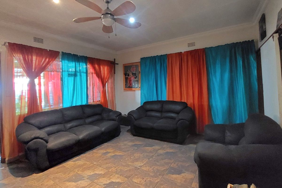 A spacious living room featuring tiled flooring, a ceiling fan, and recessed lighting, providing a functional base for interior updates.