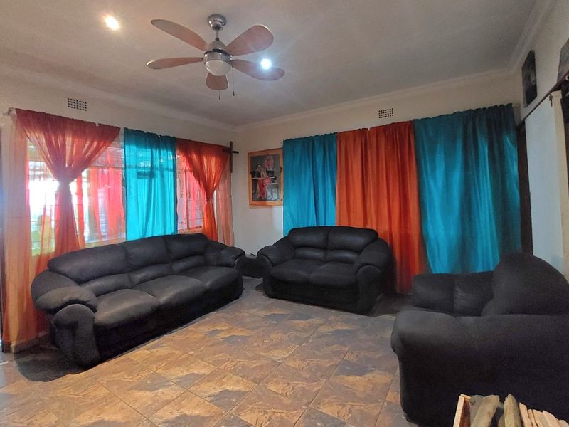 A spacious living room featuring tiled flooring, a ceiling fan, and recessed lighting, providing a functional base for interior updates.