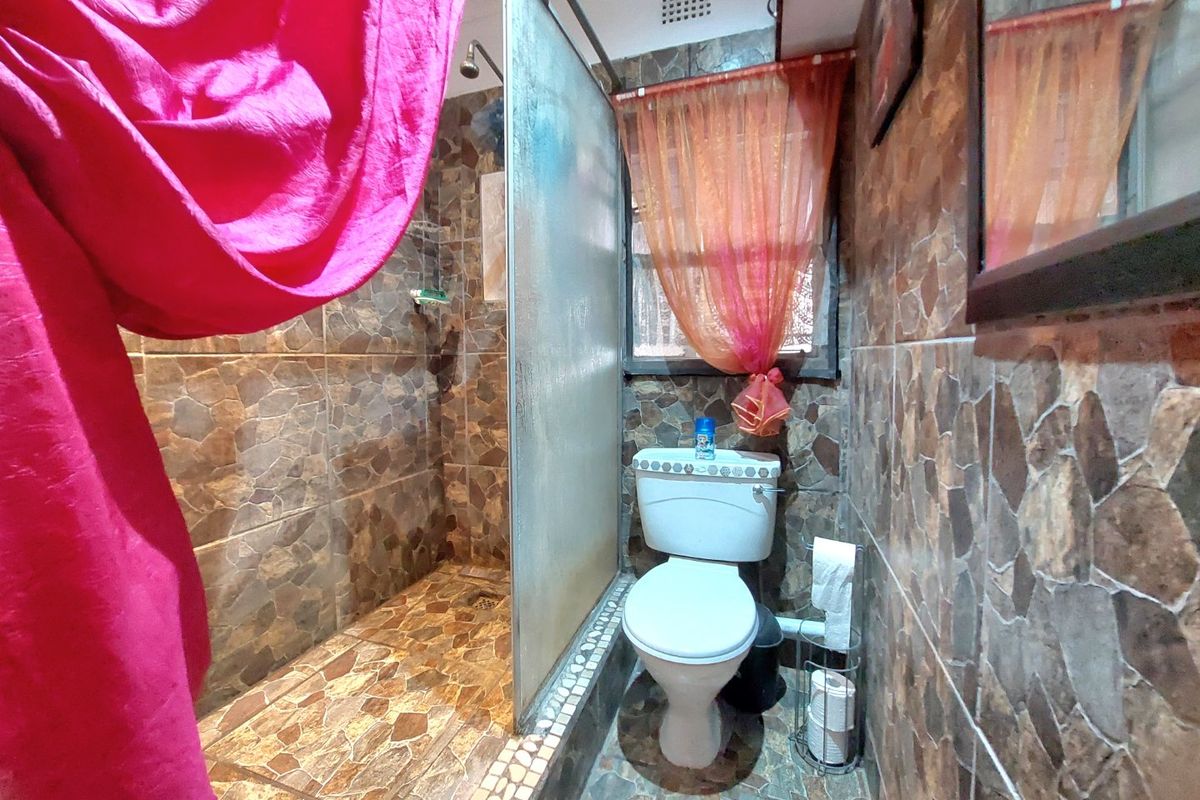 A compact bathroom featuring a walk-in shower with a glass screen and stone-look tiling throughout.