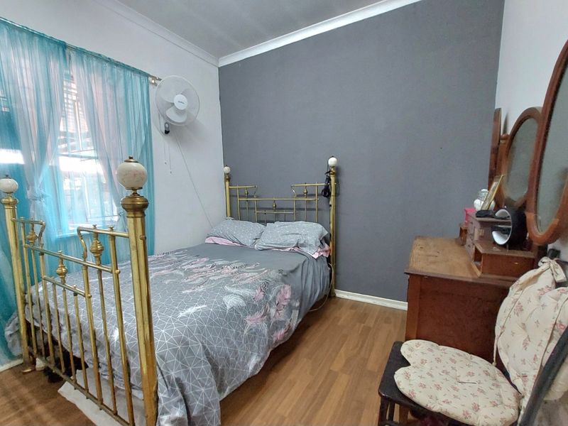 A bedroom featuring laminate flooring, a wall-mounted fan, and a feature wall, providing a functional living space.