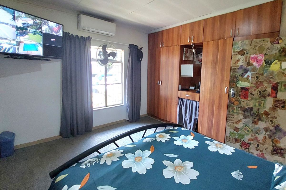 A bedroom featuring extensive built-in wooden cabinetry and a wall-mounted air conditioning unit.