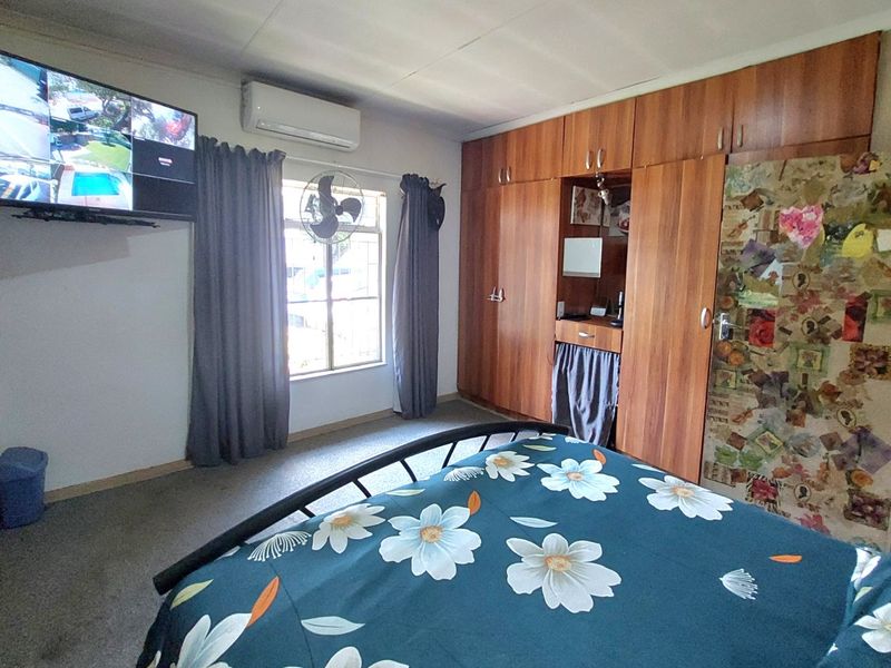 A bedroom featuring extensive built-in wooden cabinetry and a wall-mounted air conditioning unit.