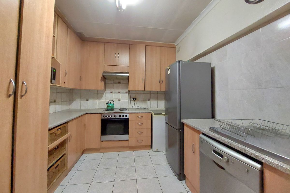 A functional kitchen featuring laminate cabinetry, tiled splashbacks, built-in oven with extractor fan, and tiled flooring.