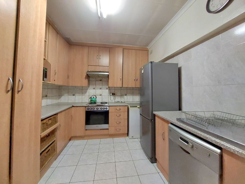 A functional kitchen featuring laminate cabinetry, tiled splashbacks, built-in oven with extractor fan, and tiled flooring.