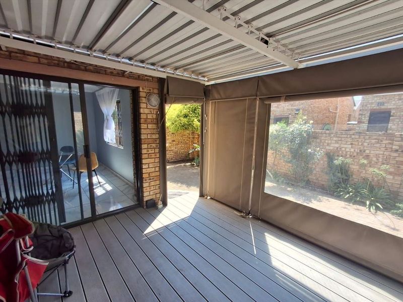 Covered patio area featuring composite decking, roll-up canvas blinds, and direct access to the garden through sliding glass doors.