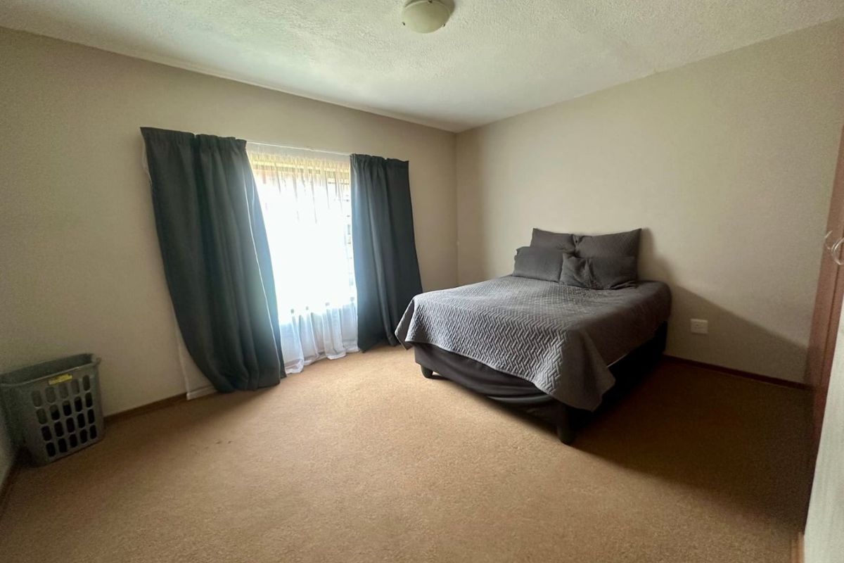 A standard bedroom featuring carpeted flooring and a built-in cupboard, providing a functional and neutral living space.