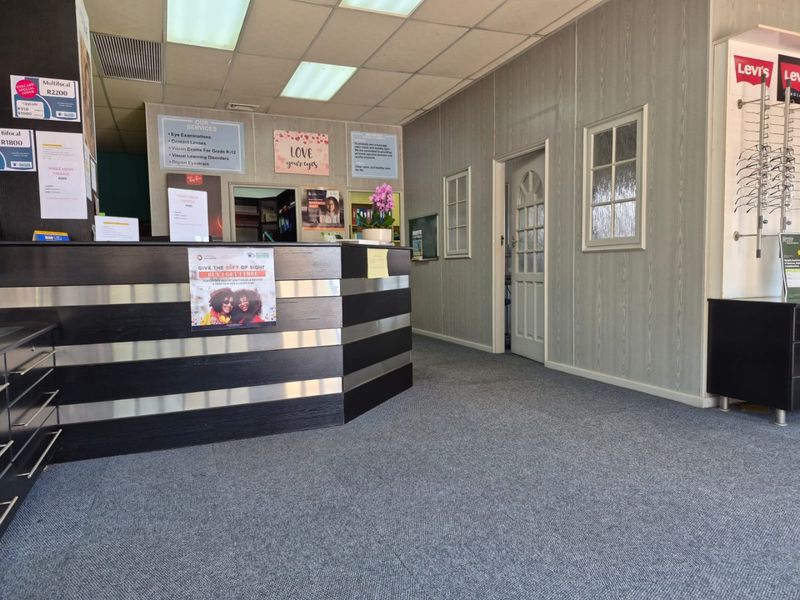 Commercial reception area featuring a built-in service desk, carpeted flooring, and panelled wall finishes, suitable for a professional office or retail environment.