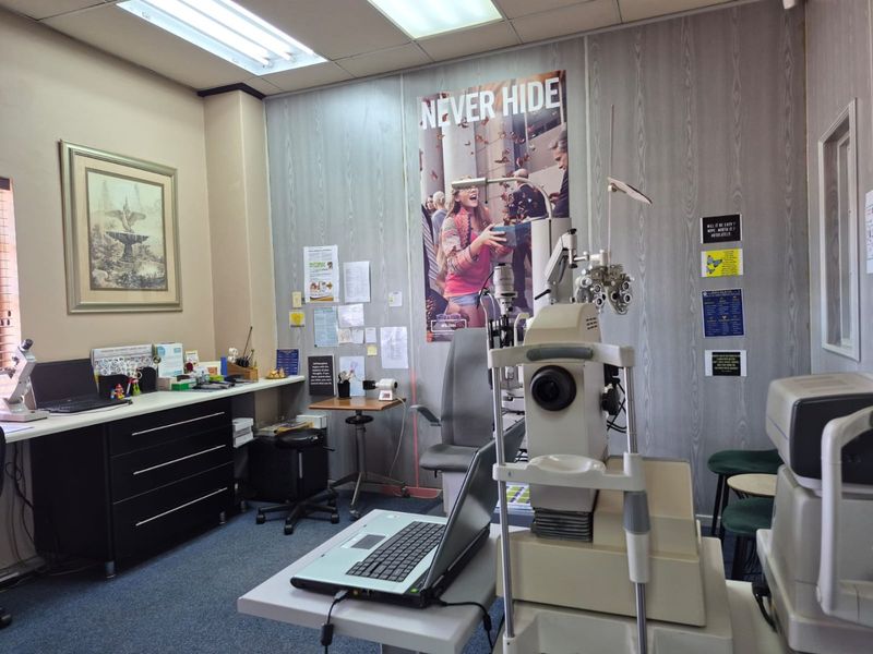 A functional commercial office space currently utilized as an optometry examination room, featuring built-in cabinetry and standard office lighting.