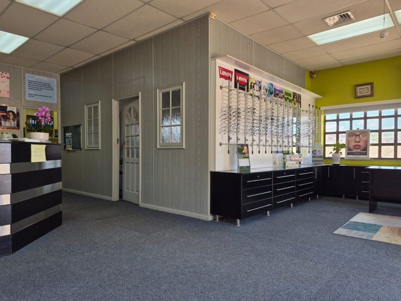 Commercial office space featuring a reception area, built-in cabinetry, grid windows, and suspended ceiling tiles, suitable for a professional practice or retail environment.