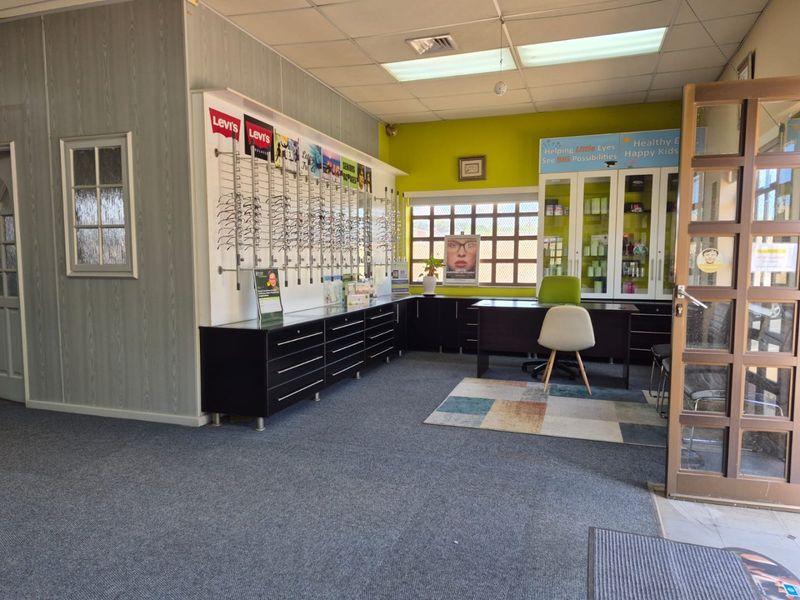 Commercial office space featuring built-in display cabinetry, fitted shelving, and suspended ceiling, suitable for a retail or professional practice environment.