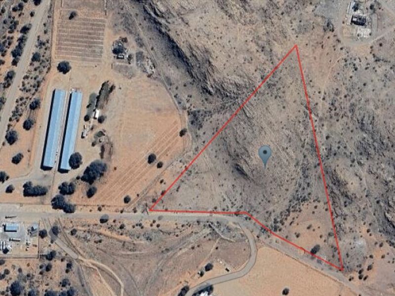 Aerial view of a large, undeveloped triangular plot of land with surrounding rural infrastructure and access roads.