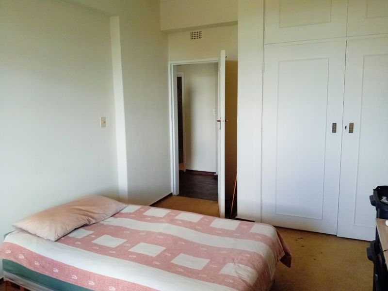 A bedroom featuring built-in cupboards and carpeted flooring, providing a functional space with potential for cosmetic updates.