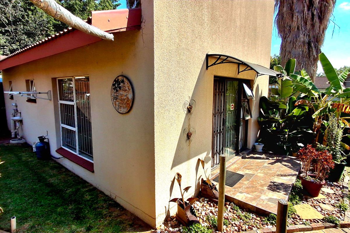 Rear exterior view of the property featuring a small tiled patio, security gate, and external wash basin area.
