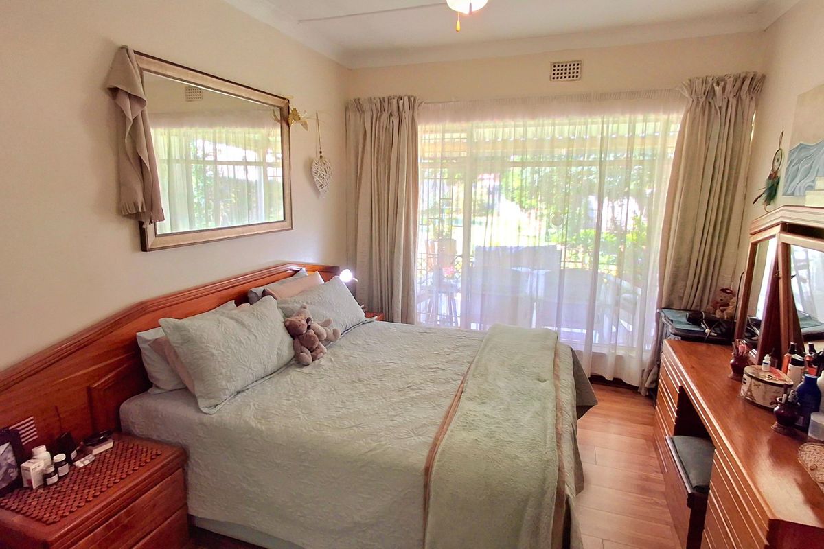 A cozy bedroom featuring laminate flooring, a ceiling fan, and a large sliding glass door providing natural light and access to the outdoor area.