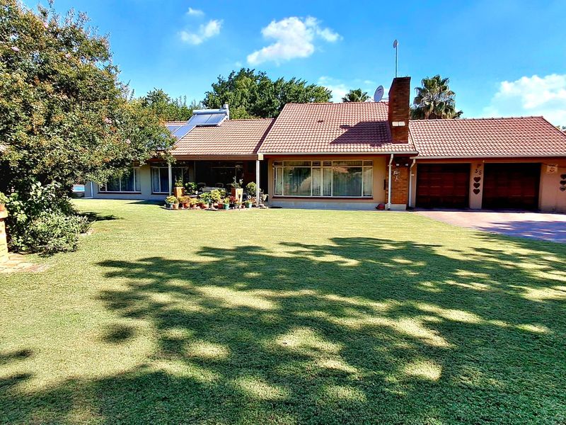 A well-maintained single-story family home featuring a tiled roof, double garage, and a spacious front lawn with a decorative brick wishing well.