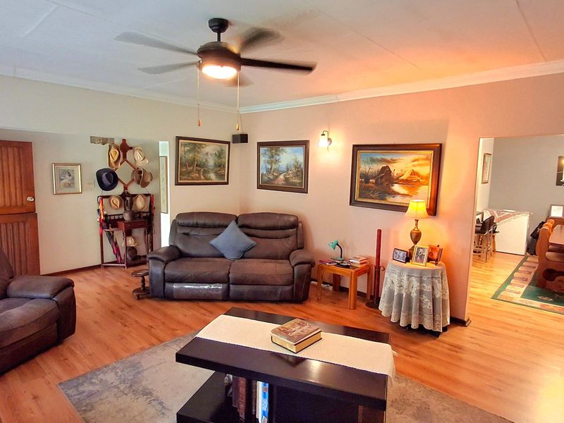 Spacious open-plan living and dining area featuring laminate flooring, a ceiling fan, and neutral wall finishes with integrated lighting.